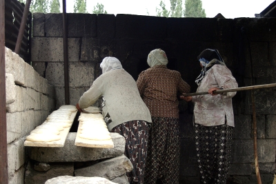 women baking flatbread at cement block oven